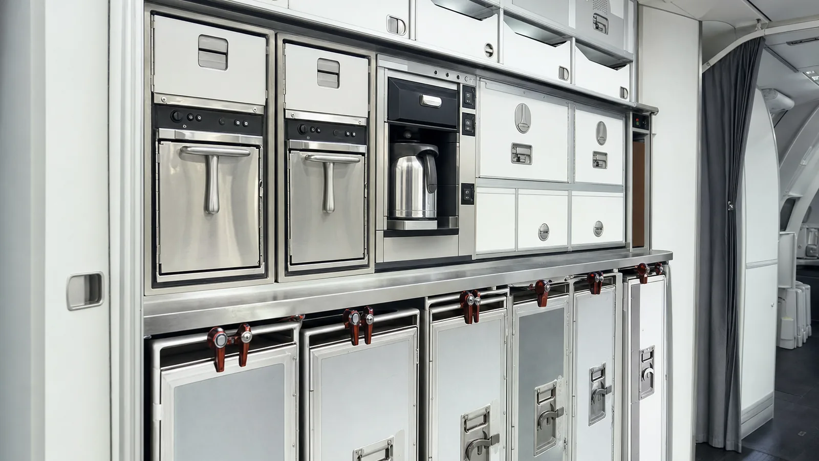 Airliner galley with stowed service trolleys, ovens and a beverage maker